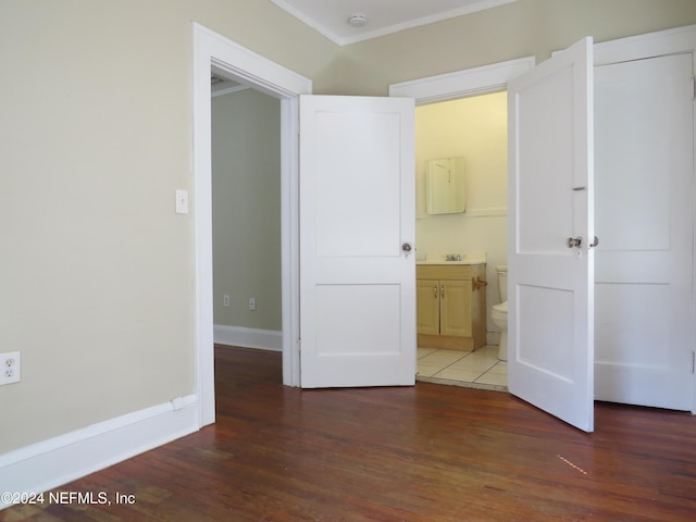 unfurnished bedroom with connected bathroom, dark hardwood / wood-style floors, ornamental molding, and sink