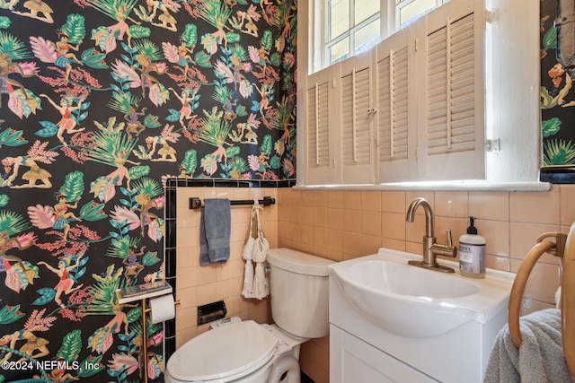 bathroom featuring toilet, vanity, and tile walls