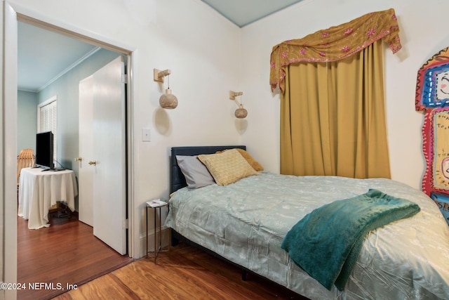 bedroom with ornamental molding and wood-type flooring