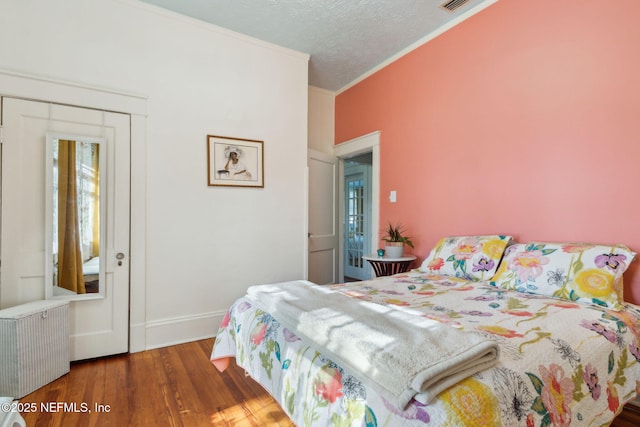 bedroom with wood-type flooring, radiator heating unit, ornamental molding, and a textured ceiling