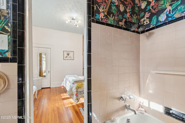 bathroom with a textured ceiling, tiled shower / bath, and wood-type flooring