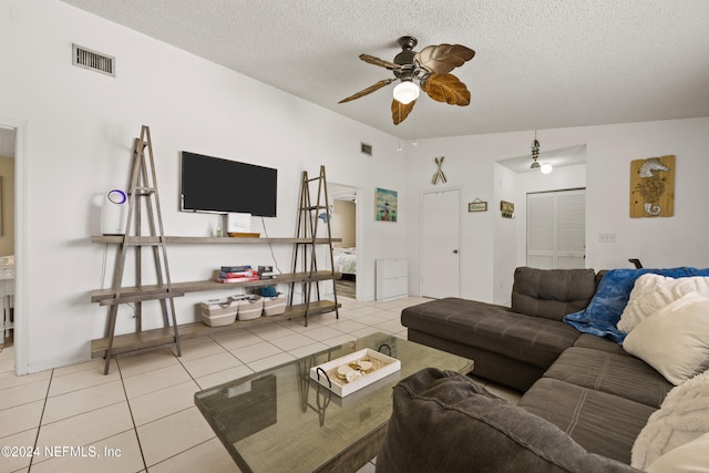 living room with ceiling fan, light tile patterned floors, and a textured ceiling