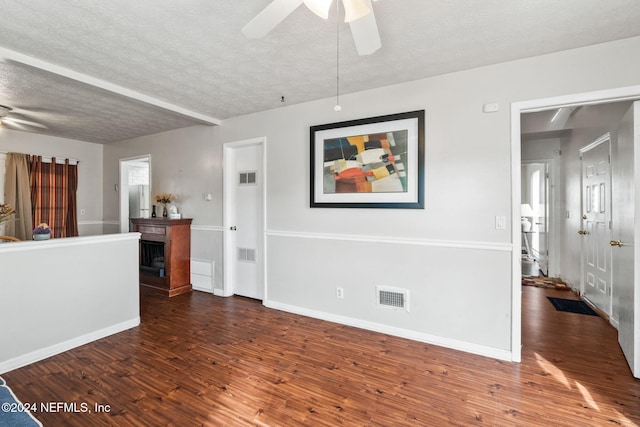 unfurnished living room featuring ceiling fan, dark hardwood / wood-style flooring, and a textured ceiling