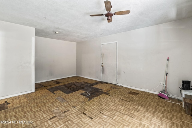 empty room with ceiling fan, a textured ceiling, and light parquet flooring