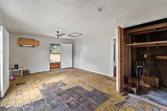 unfurnished living room with ceiling fan, dark parquet flooring, and a textured ceiling