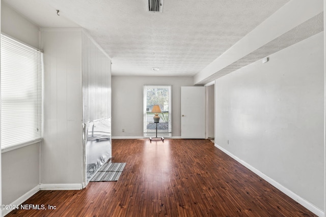 empty room featuring a textured ceiling and dark hardwood / wood-style flooring