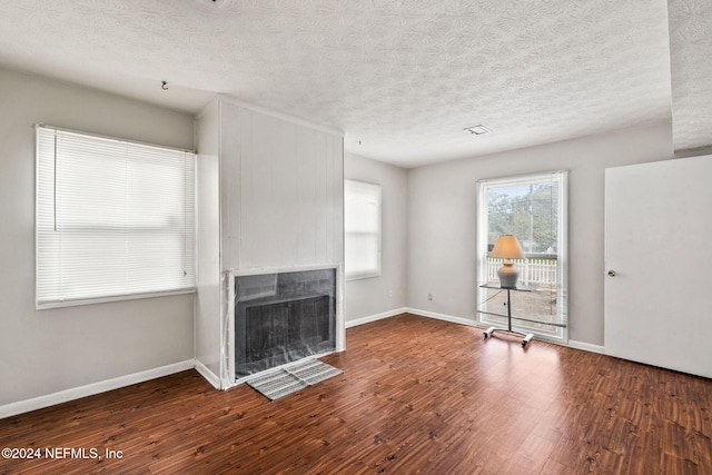 unfurnished living room featuring a textured ceiling and dark hardwood / wood-style floors