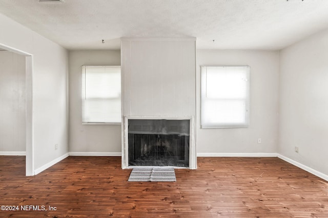 unfurnished living room with hardwood / wood-style floors, a textured ceiling, and a wealth of natural light