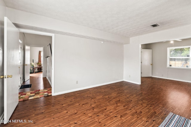 empty room featuring a textured ceiling and dark hardwood / wood-style flooring