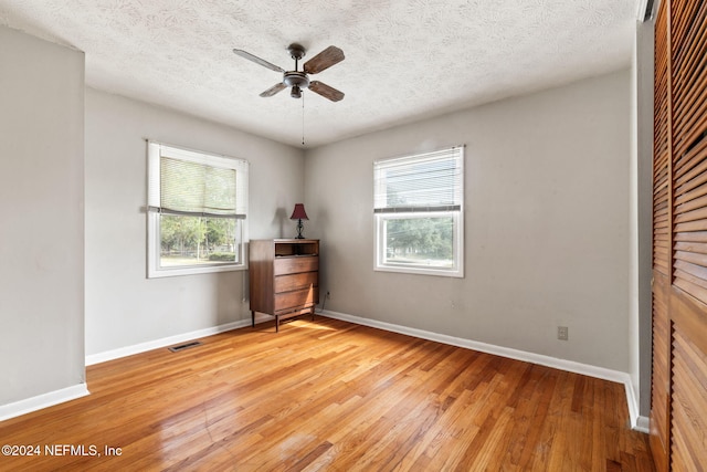 unfurnished bedroom featuring multiple windows, a textured ceiling, and hardwood / wood-style flooring