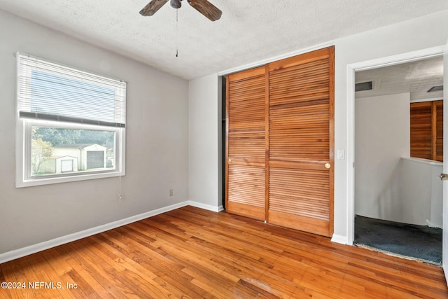 unfurnished bedroom featuring a textured ceiling, light hardwood / wood-style flooring, a closet, and ceiling fan