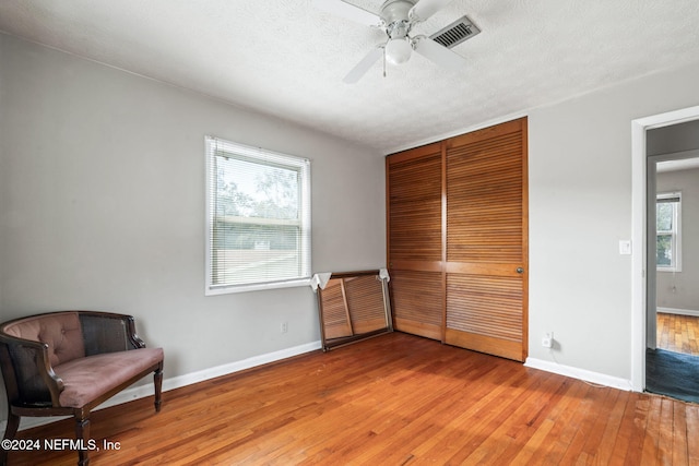 bedroom featuring hardwood / wood-style flooring, ceiling fan, multiple windows, and a closet