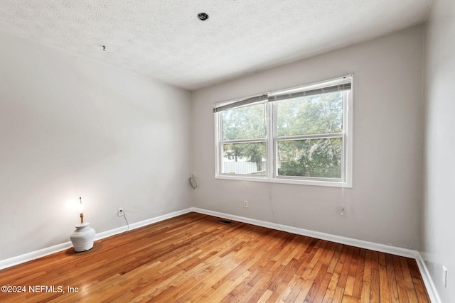 empty room with a textured ceiling and light wood-type flooring