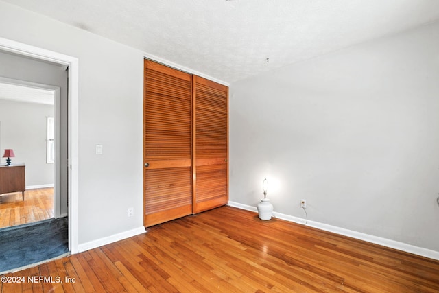 unfurnished bedroom with wood-type flooring, a textured ceiling, and a closet