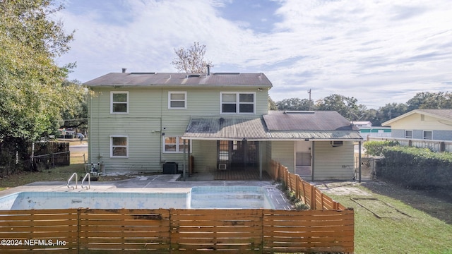 back of property featuring central AC, a patio, and an empty pool