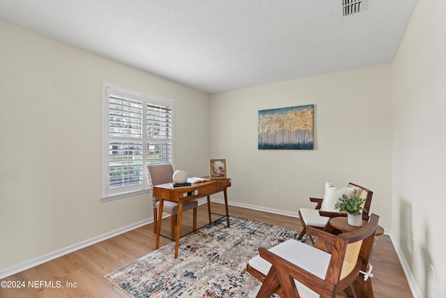 home office featuring a textured ceiling and light hardwood / wood-style flooring