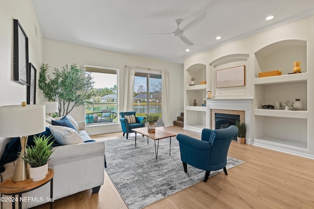 living room featuring hardwood / wood-style floors, built in features, and ceiling fan