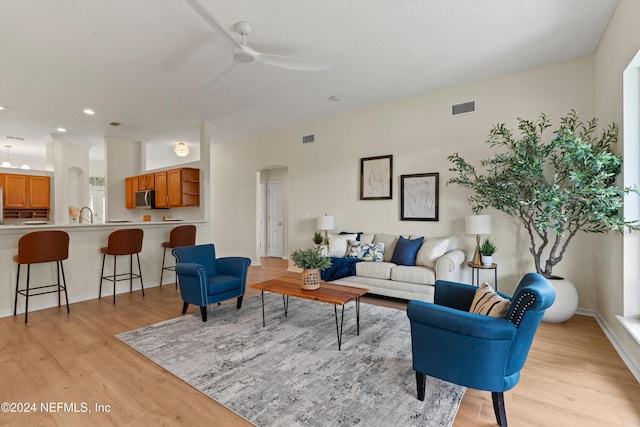 living room featuring ceiling fan, light wood-type flooring, and sink