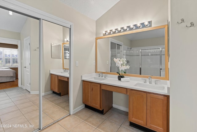 bathroom with a textured ceiling, tile patterned flooring, vanity, and vaulted ceiling