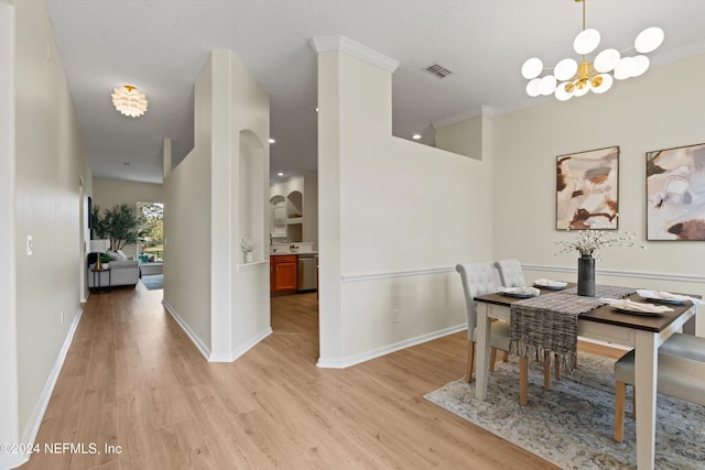 dining area featuring light hardwood / wood-style floors, crown molding, and an inviting chandelier