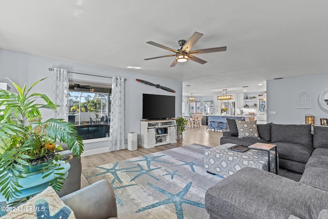 living room with ceiling fan, light hardwood / wood-style floors, and a textured ceiling