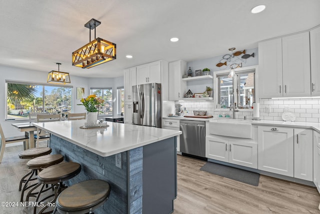 kitchen featuring white cabinets, stainless steel appliances, and hanging light fixtures