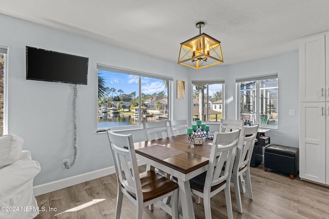 dining area with a notable chandelier, light hardwood / wood-style floors, and a textured ceiling