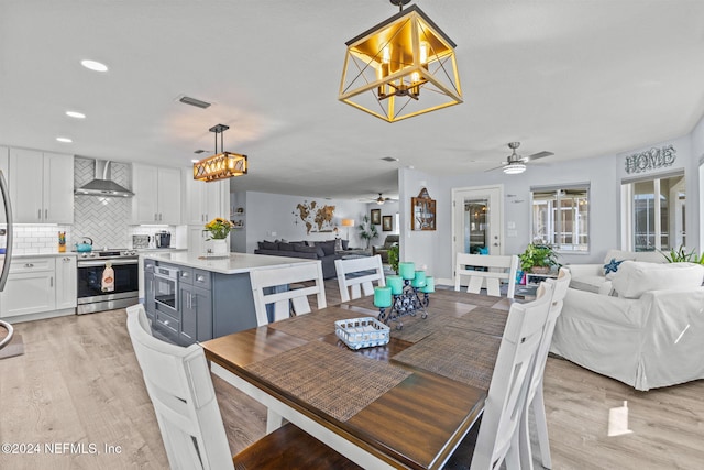 dining space with ceiling fan with notable chandelier and light hardwood / wood-style floors