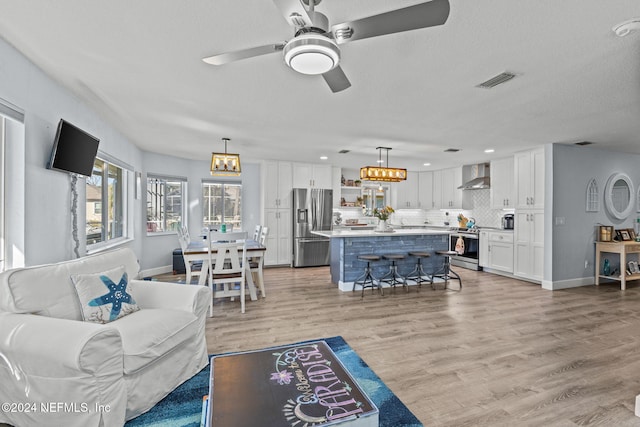 living room featuring a textured ceiling, light wood-type flooring, and ceiling fan