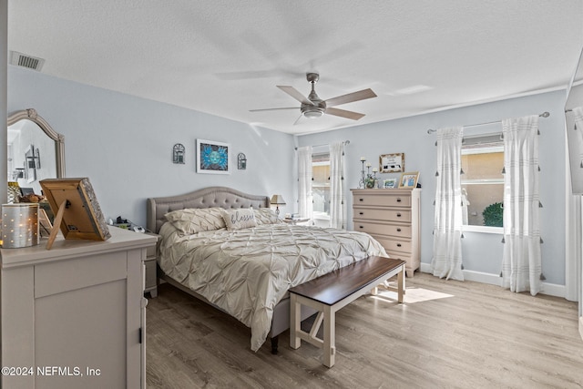 bedroom with a textured ceiling, light hardwood / wood-style floors, and ceiling fan