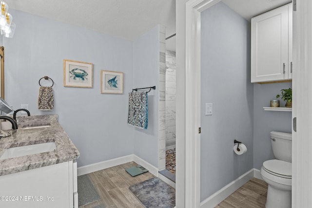 bathroom featuring a shower, hardwood / wood-style floors, vanity, and toilet