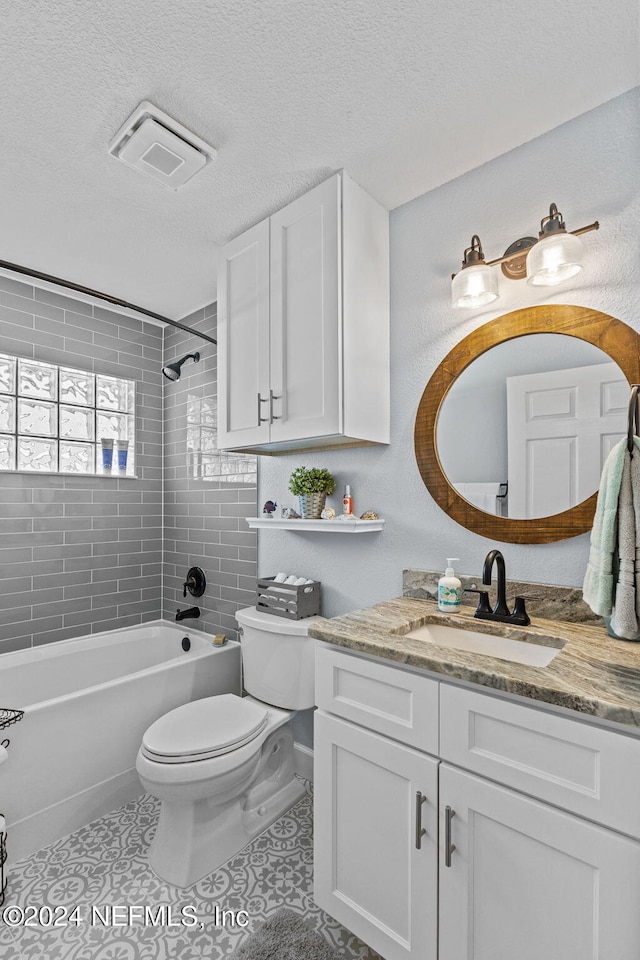 full bathroom with tile patterned floors, vanity, a textured ceiling, and tiled shower / bath