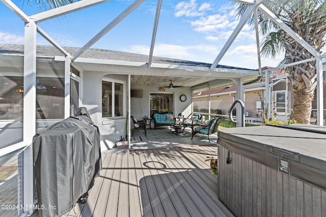 wooden terrace with outdoor lounge area, a hot tub, ceiling fan, and a lanai