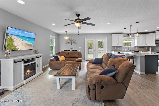 living room featuring a wealth of natural light, sink, ceiling fan, and light wood-type flooring