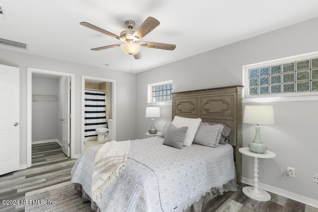 bedroom with hardwood / wood-style floors, a closet, a spacious closet, and ceiling fan