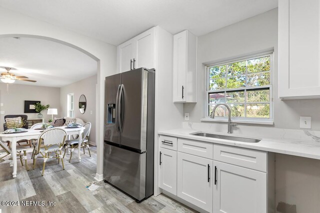 kitchen featuring sink, stainless steel fridge with ice dispenser, light stone countertops, light hardwood / wood-style floors, and white cabinetry