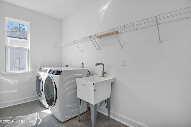 washroom with dark tile patterned flooring, laundry area, baseboards, and separate washer and dryer