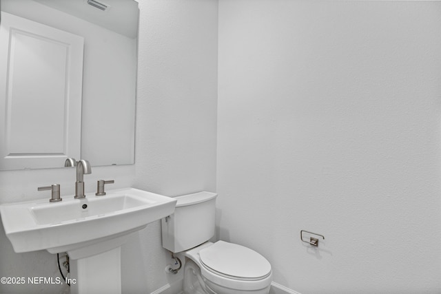 bathroom with baseboards, visible vents, a sink, and toilet