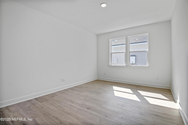 spare room featuring light wood-type flooring and baseboards