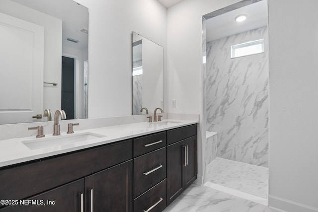 full bath featuring double vanity, marble finish floor, a marble finish shower, and a sink