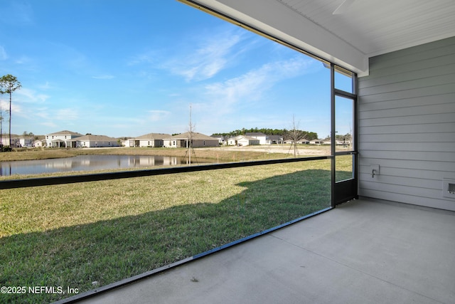 unfurnished sunroom featuring a water view and a residential view