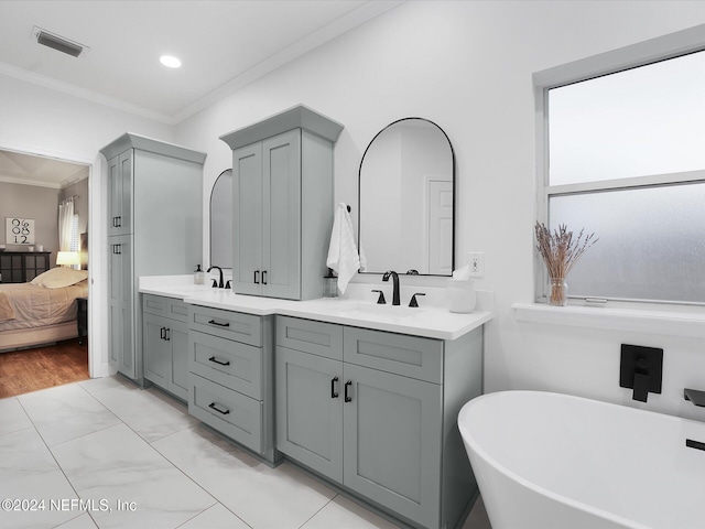 bathroom with vanity, ornamental molding, and a tub