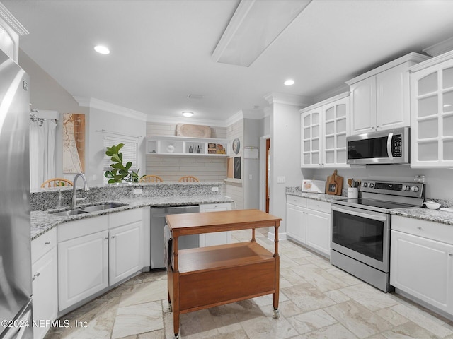 kitchen featuring light stone counters, ornamental molding, stainless steel appliances, sink, and white cabinetry