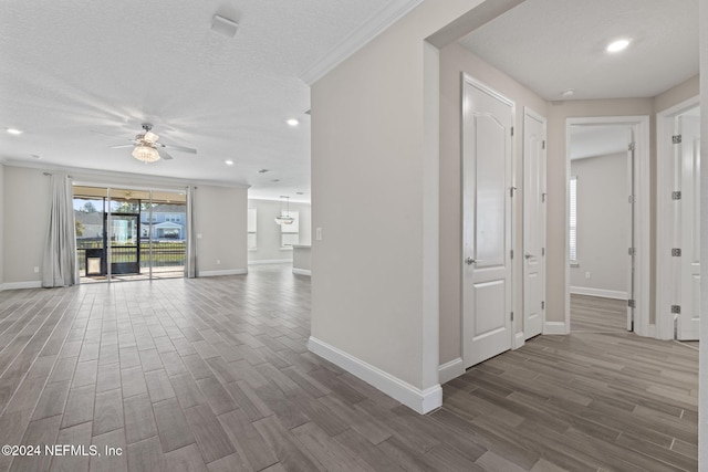 hall with hardwood / wood-style floors, ornamental molding, and a textured ceiling