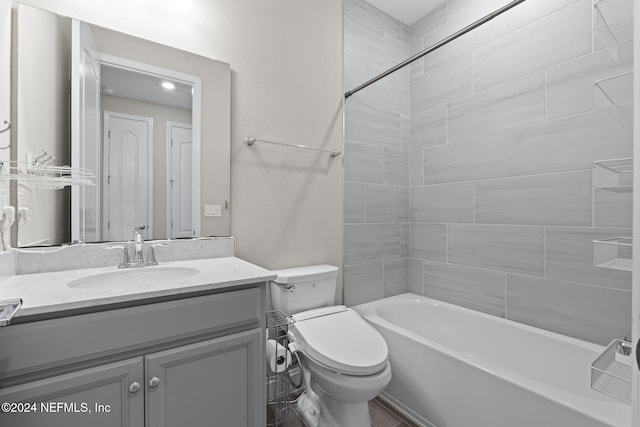 full bathroom featuring vanity, tiled shower / bath combo, and toilet