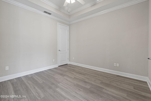 spare room with a tray ceiling, hardwood / wood-style flooring, ceiling fan, and ornamental molding