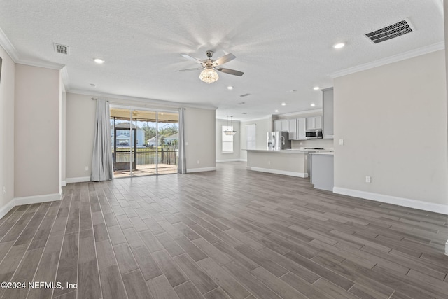 unfurnished living room featuring a textured ceiling, dark hardwood / wood-style floors, and ornamental molding