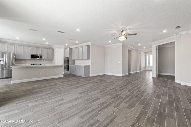 unfurnished living room featuring a textured ceiling, ceiling fan, wood-type flooring, and ornamental molding