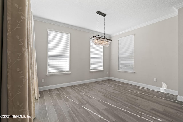 unfurnished room with a textured ceiling, dark hardwood / wood-style floors, ornamental molding, and a notable chandelier