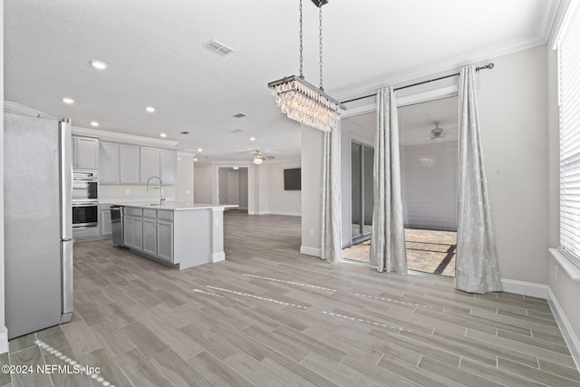 kitchen with plenty of natural light, an island with sink, pendant lighting, and fridge